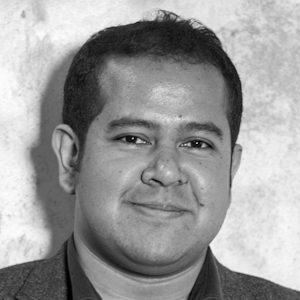 A man with short hair wearing a shirt with an open collar.