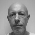 A bald man looking into the camera.